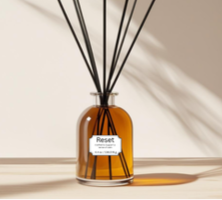 Glass reed diffuser labeled “Reset” with natural reeds, surrounded by lavender, bergamot, chamomile, and patchouli — calming essential oil blend for relaxation and anxiety relief.