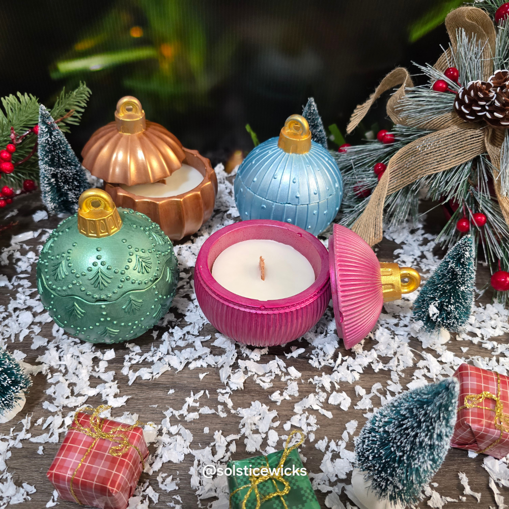 Decorative candles shaped like Christmas ornaments on a festive background with trees and lights.